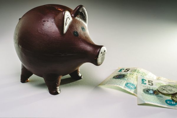 Piggy bank with pounds on bills and coins before brexit.